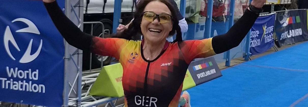 Frau läuft mit erhobenen Händen über Ziellinie