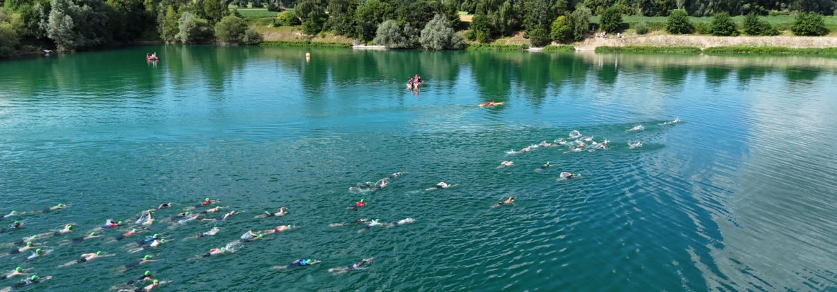 Blick auf See mit Schwimmern. Ufer und Landschaft im Hintergrund