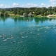 Blick auf See mit Schwimmern. Ufer und Landschaft im Hintergrund