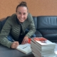 Portrait einer lachenden Frau mit Stapel Bücher