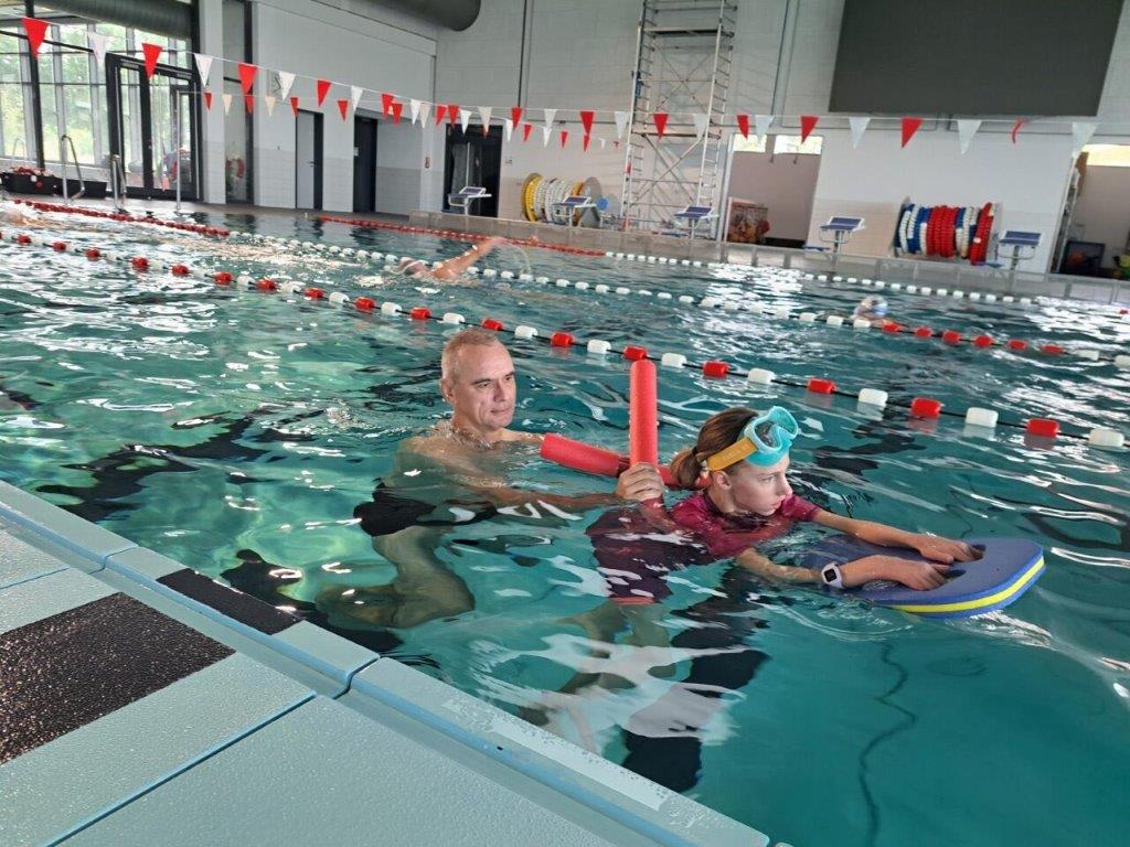 Schwimmlehrer und behinderte Schwimmschülerin im Wasser