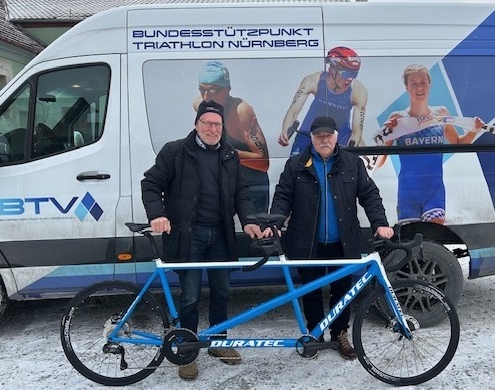 Zwei Männer vor Teambus mit Tandem