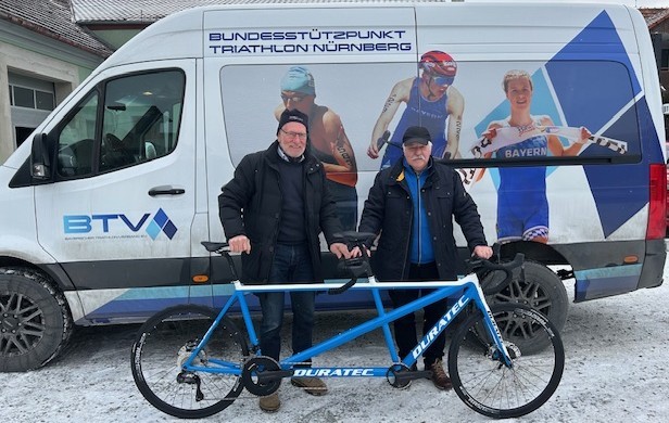 Zwei Männer vor Teambus mit Tandem