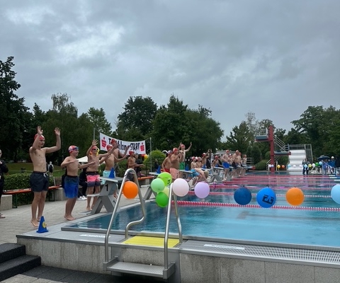 Blick auf ein Schwimmbad mit bunten Luftballons und jungen Sportlern