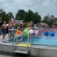 Blick auf ein Schwimmbad mit bunten Luftballons und jungen Sportlern