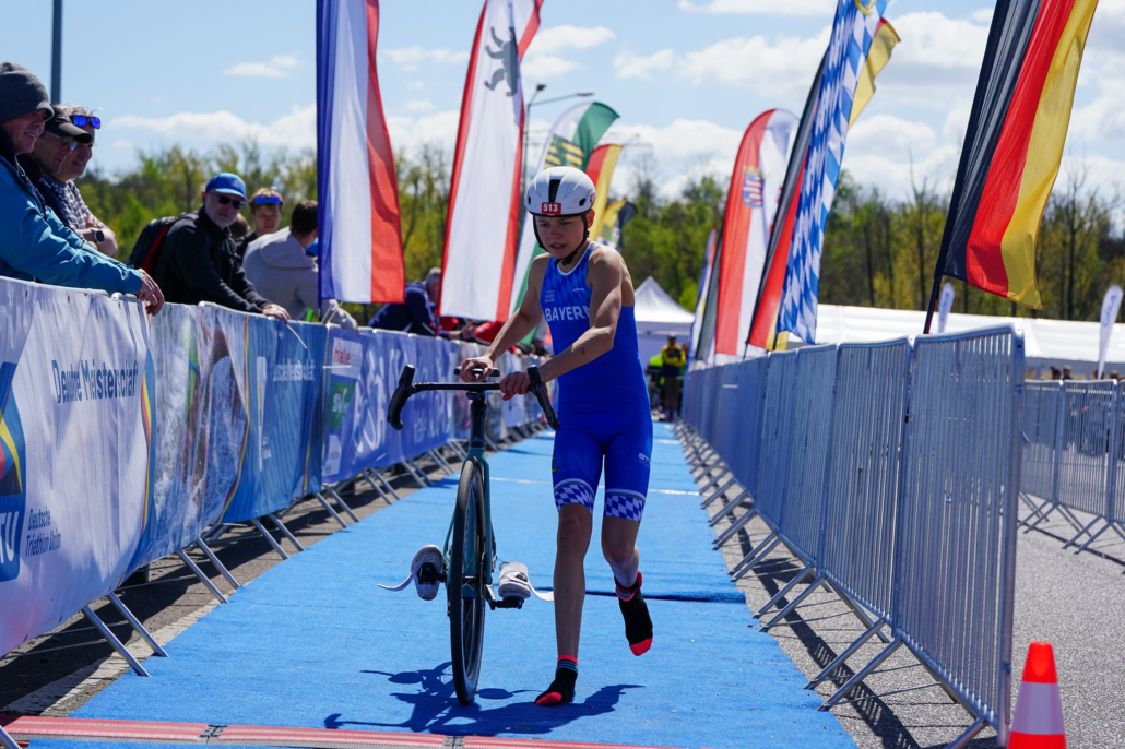 Sportler schiebt sein Rad über blauen Teppich