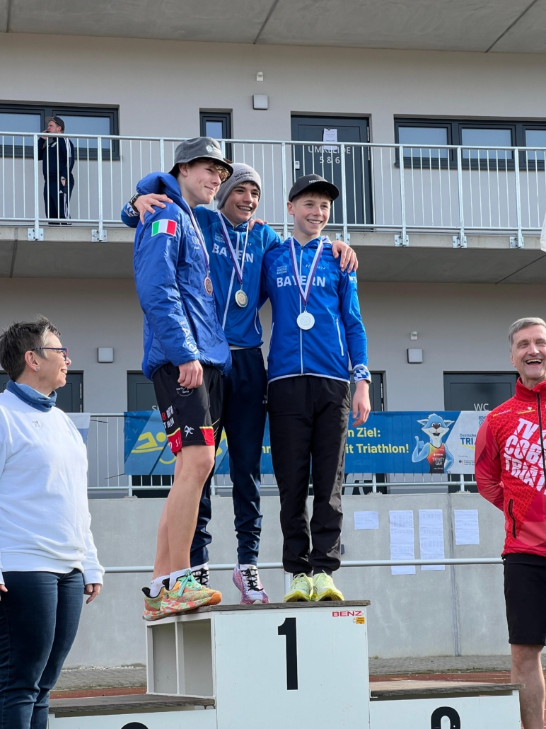 Drei jungen in blauen Jacken auf dem Podium