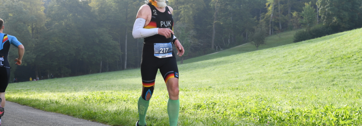 Älterer Sportler in Deutschland-Rennanzug beim Laufen