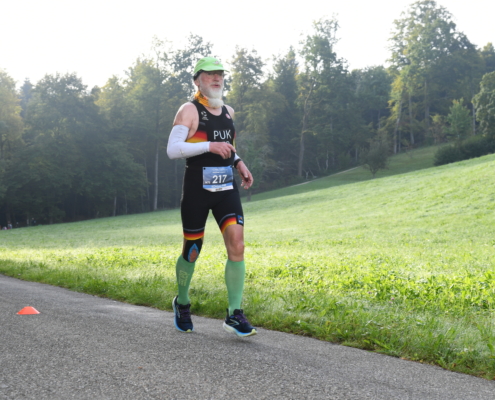 Älterer Sportler in Deutschland-Rennanzug beim Laufen
